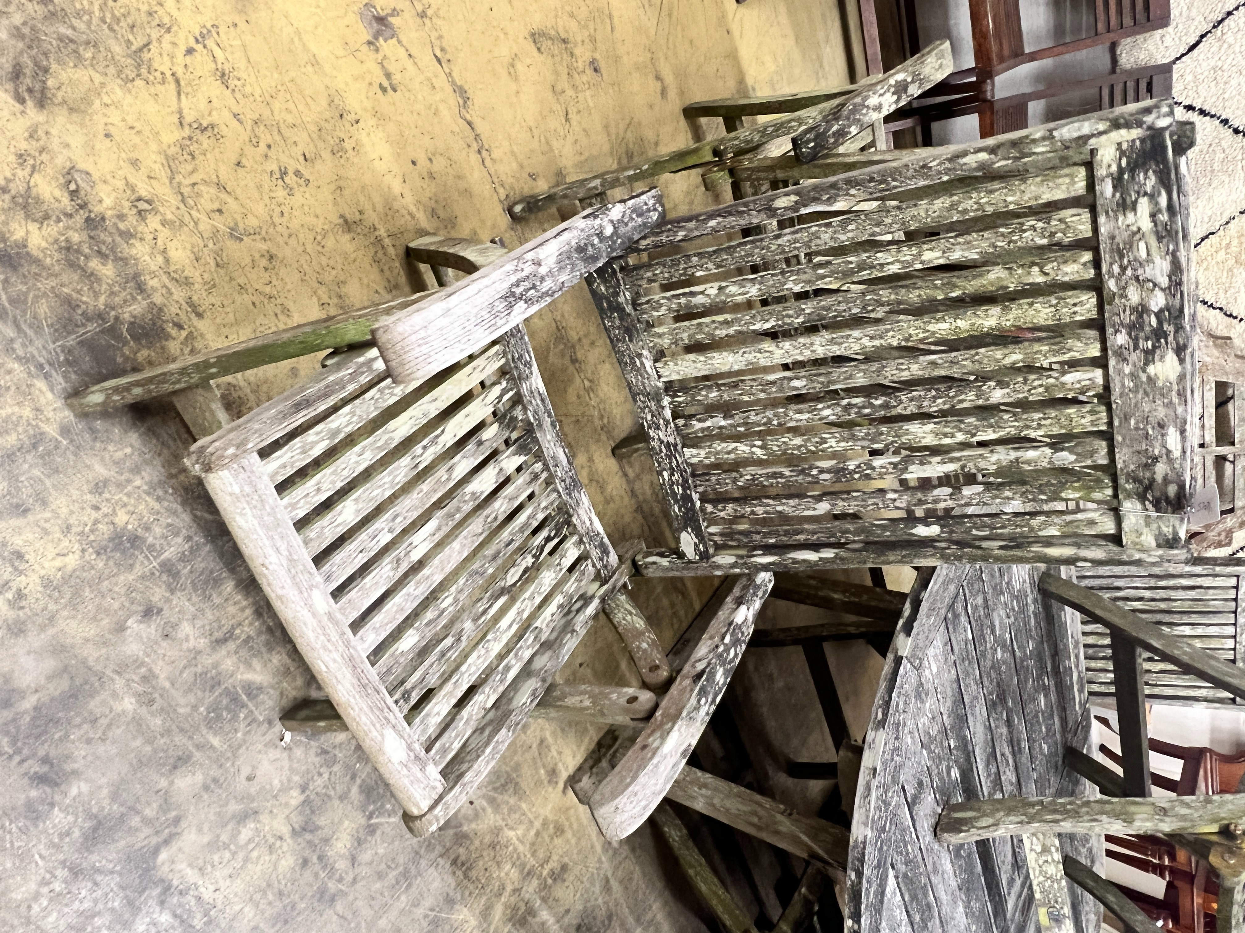 A weathered teak oval extending garden table, extended 250cm, width 109cm, height 73cm, together with six Neptune weathered teak folding garden elbow chairs